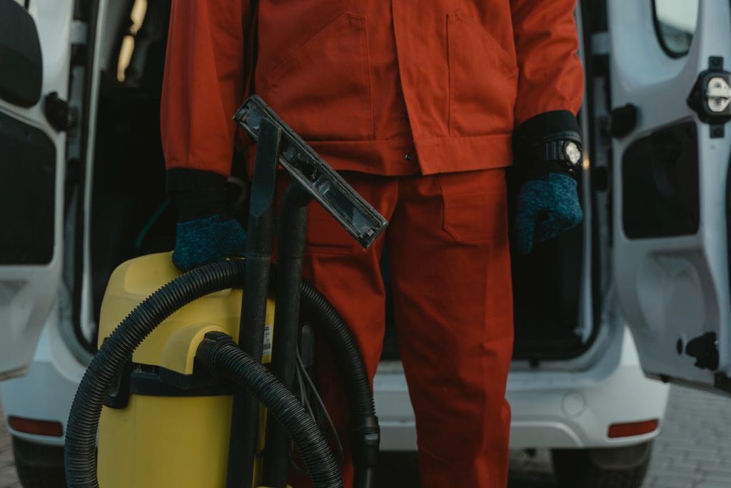 Person in red overalls holding a vacuum cleaner.